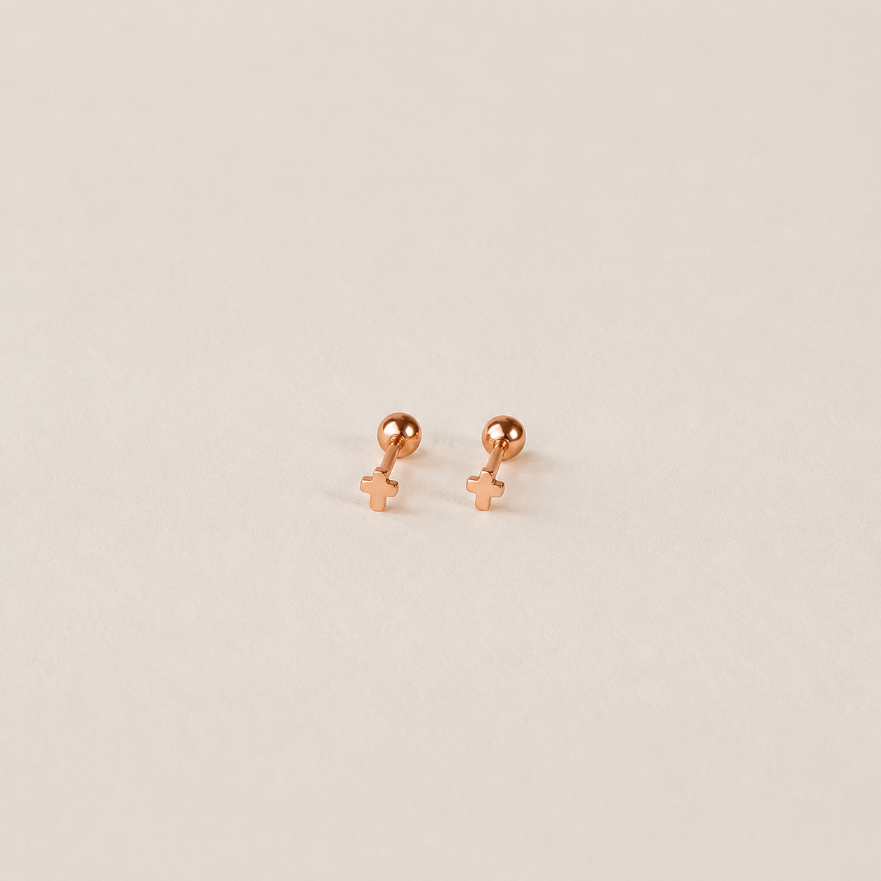 Rose gold earrings on a beige background